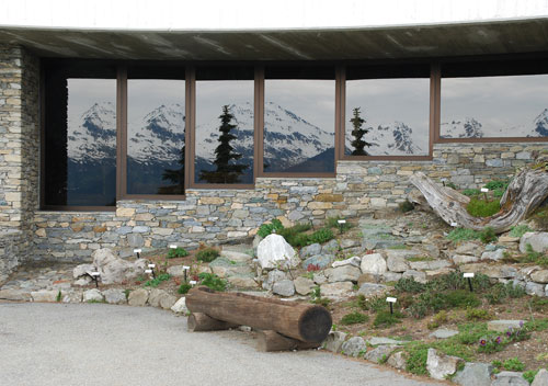 Vetrata di fondo, adiacente all'ingresso, e il giardino alpino allestito nel sagrato