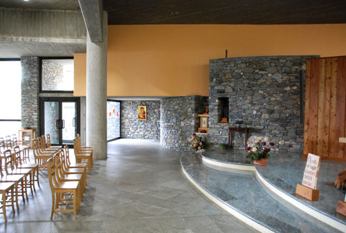 Parete curva della cappella dell'adorazione eucaristica, con il taglio per il tabernacolo; a sinistra, l'ingresso laterale e la cappella mariana