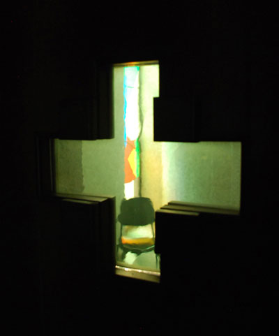 Il confessionale, visto tramite l'apertura a croce praticata nella porta di ingresso