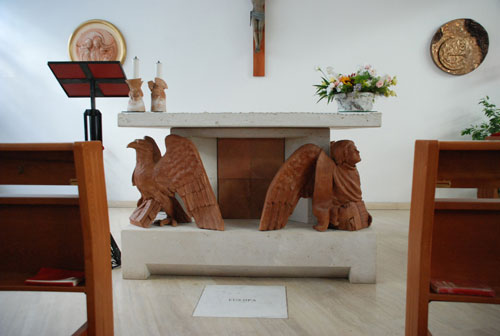 L'altare della cappella feriale (Cordelia von den Steinen) e, sulla parete di fondo, il tabernacolo e il tondo della Sacra Famiglia (Alfea Ciccone)