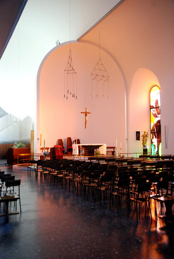 Lo spazio luminoso della volta che unisce e sovrasta le due navate, culminando nello spazio absidale oltre il guscio del presbiterio.